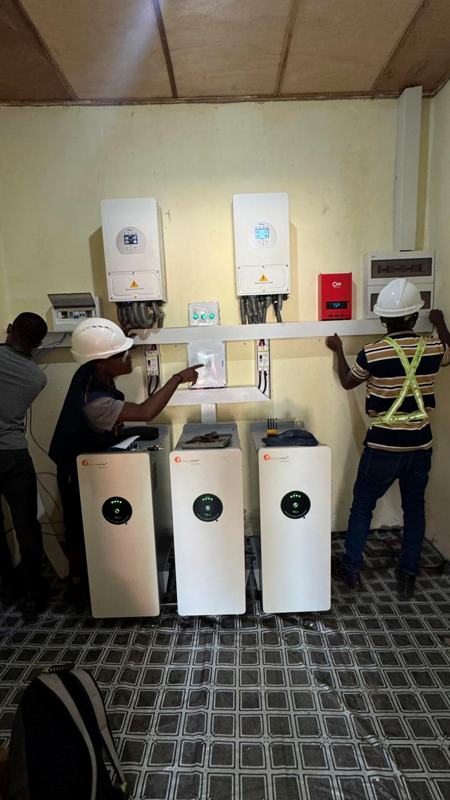 Technicians wiring inverters and battery towers in an equipment room