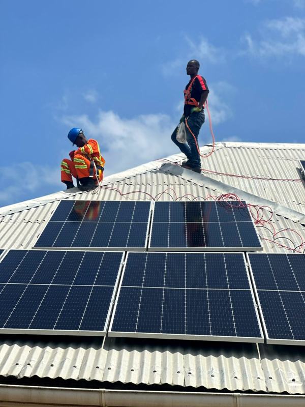 Two technicians fixing panels on a corrugated roof