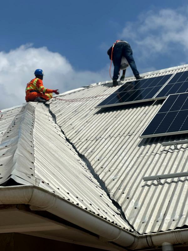 Installers working across the ridge of a metal roof