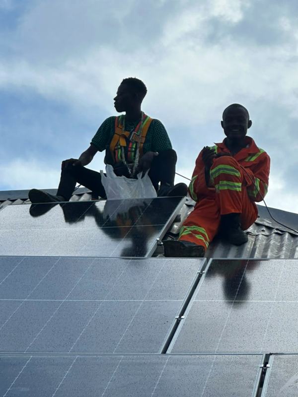 Two crew members seated among panels on a roof