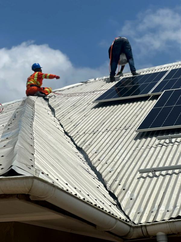 Two installers on the ridge of a roof, one pointing at the sky